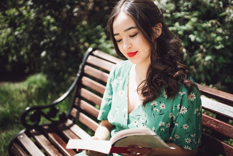 Asian young woman reading a novel at a public park.