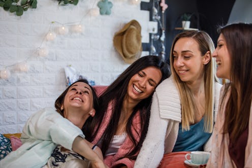 Copy space shot of four cheerful women sitting in bed, having tea, relaxing, bonding and laughing to...