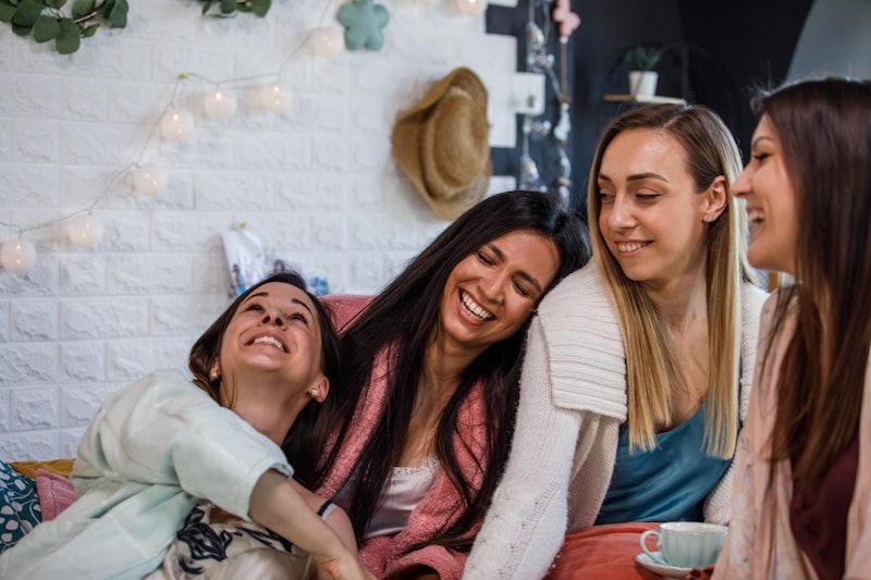 Copy space shot of four cheerful women sitting in bed, having tea, relaxing, bonding and laughing to...