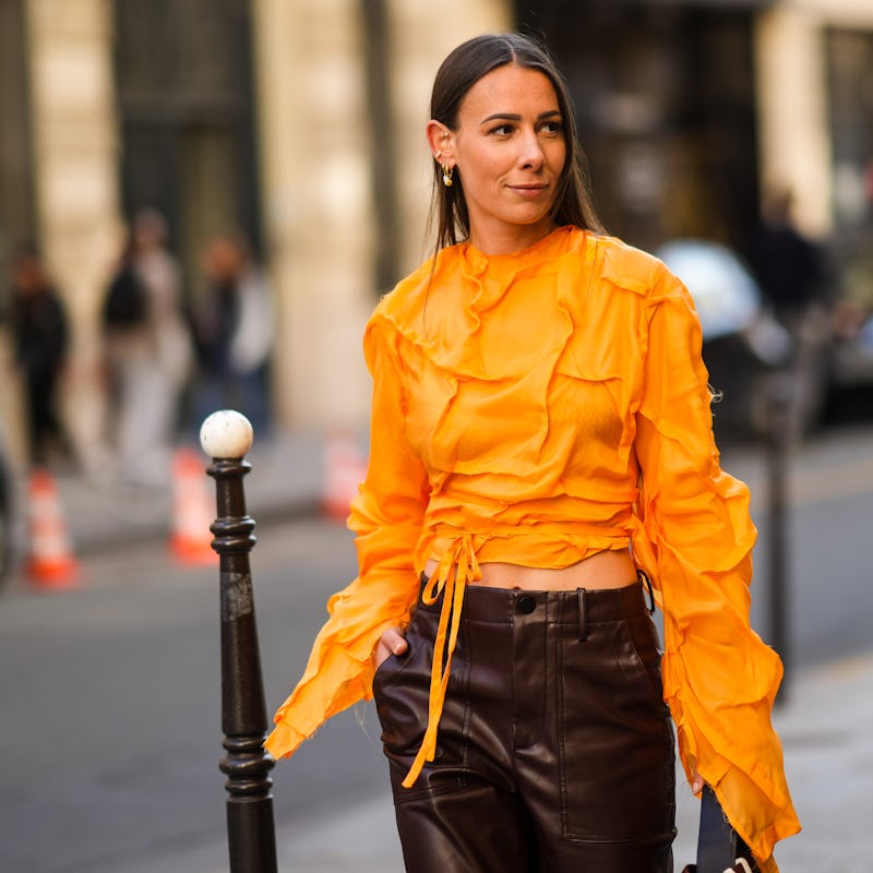 PARIS, FRANCE - JUNE 24: Alice Barbier wears an earring, an orange cropped top with long sleeves and...