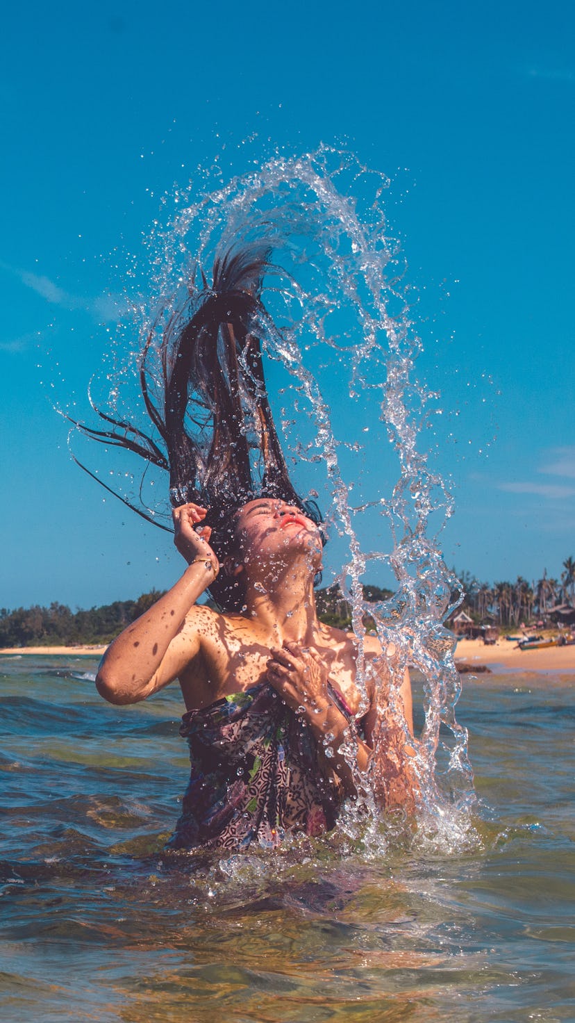 A person tosses their hair over their head as they emerge from the water. Even if you're new to swim...