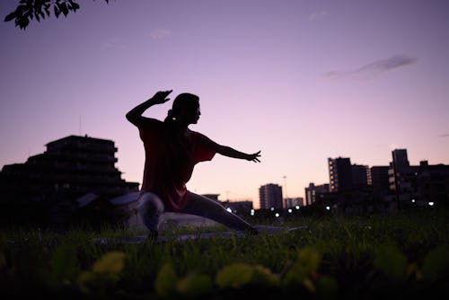 Woman doing taichi in empty city early in the morning. Here's how tai chi vs. yoga compare.