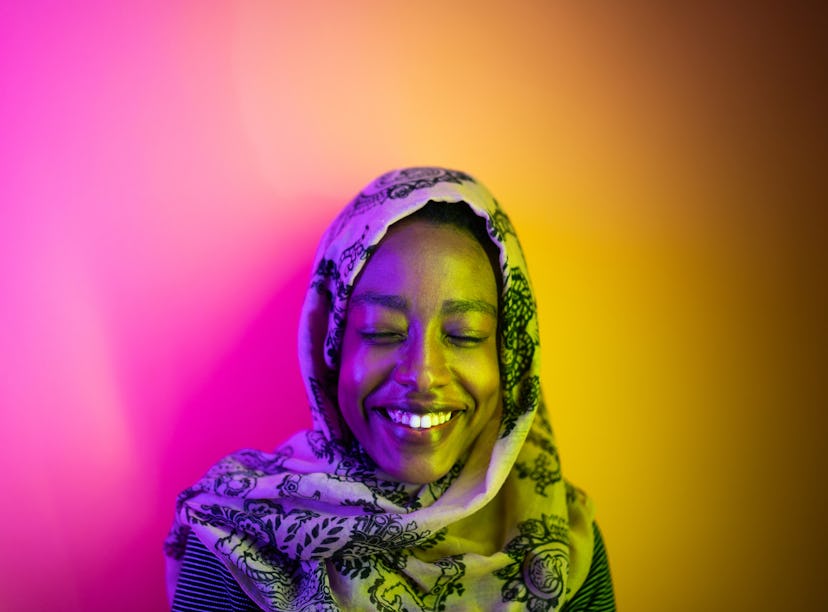 Young woman wearing a hijab, under neon lights, having the best week of July 5, 2021, per her zodiac...