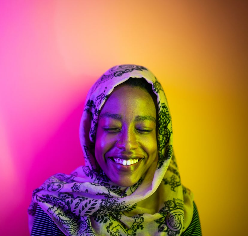 Young woman wearing a hijab, under neon lights, having the best week of July 5, 2021, per her zodiac...