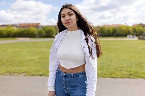 Portrait of an attractive teenage girl standing at Tempelhofer park. Female in casuals looking at ca...