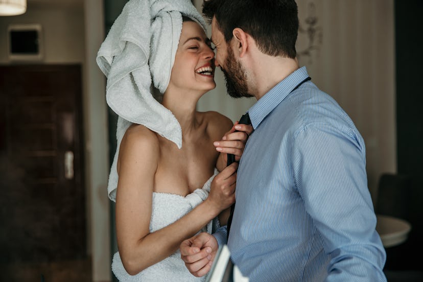 A beautiful woman helping her husband to get ready for work, morning preparation of young married co...