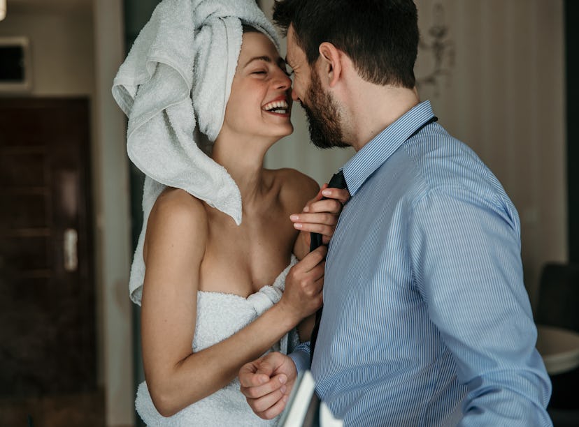 A beautiful woman helping her husband to get ready for work, morning preparation of young married co...