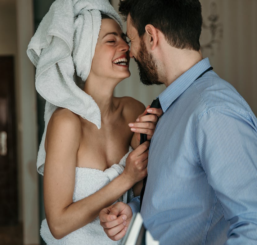 A beautiful woman helping her husband to get ready for work, morning preparation of young married co...