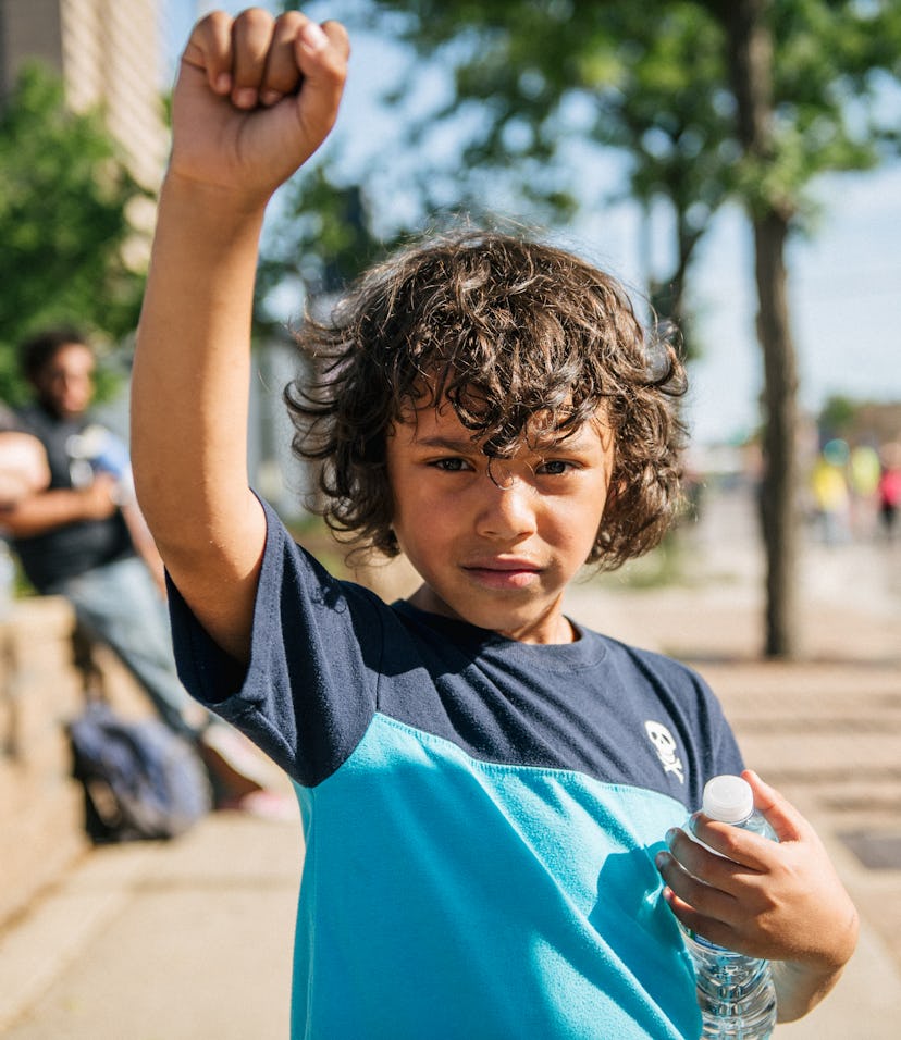 A boy raises his fist in the air as protesters rally in front of the 2nd Precinct Police Station dur...