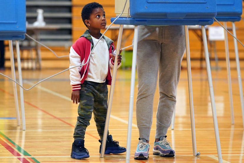 Karter Benson, 4, watches his mom Ceara Hinton vote at the North High School gymnasium polling locat...