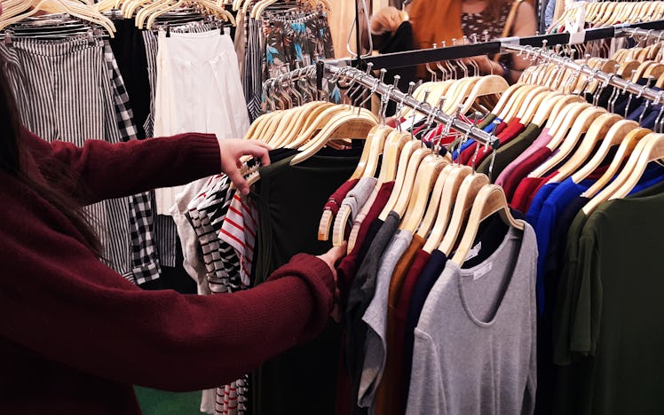 A person looking through clothing racks at a store