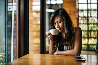 A woman drinks coffee. Caffeine sensitivity symptoms include high blood pressure.