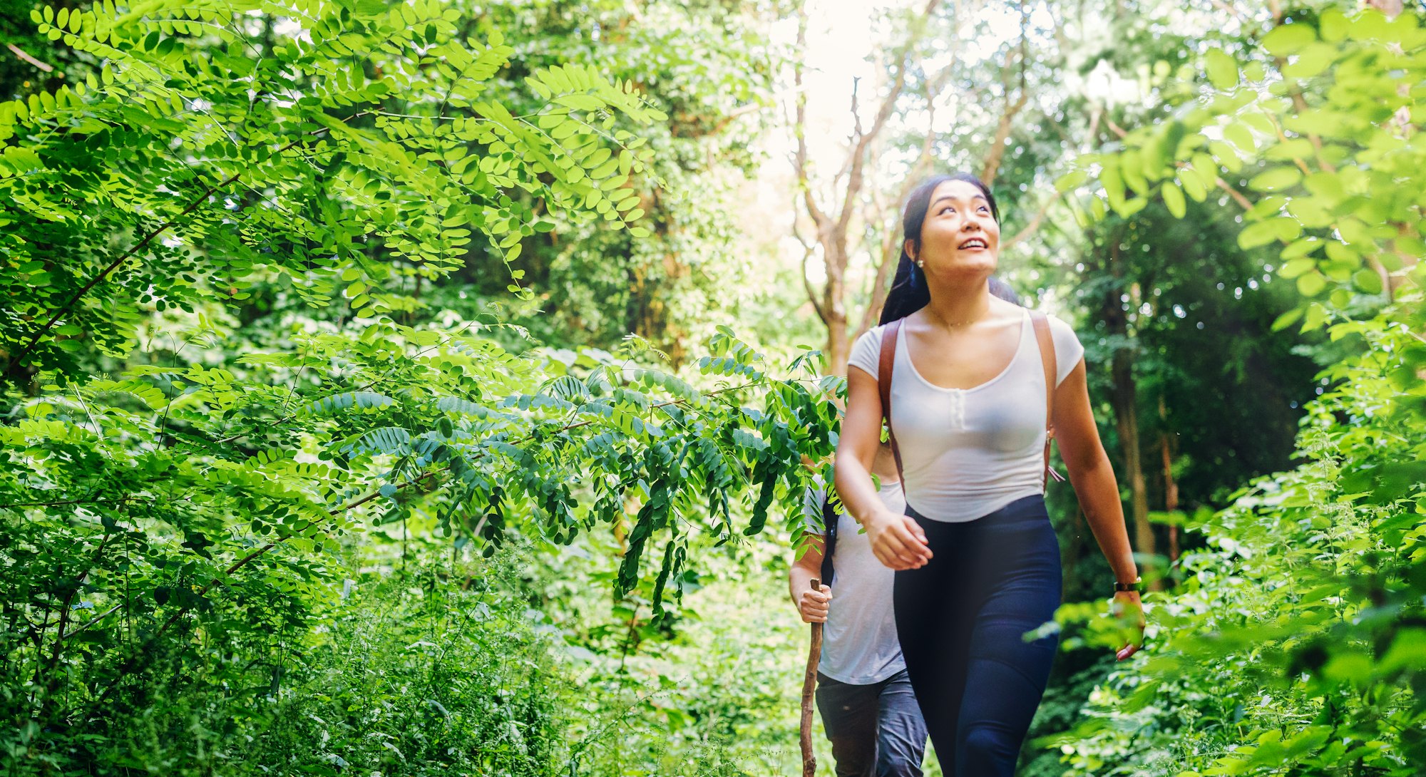 A person wears a white shirt while walking in front of a friend on a trail. You don't have to be sit...