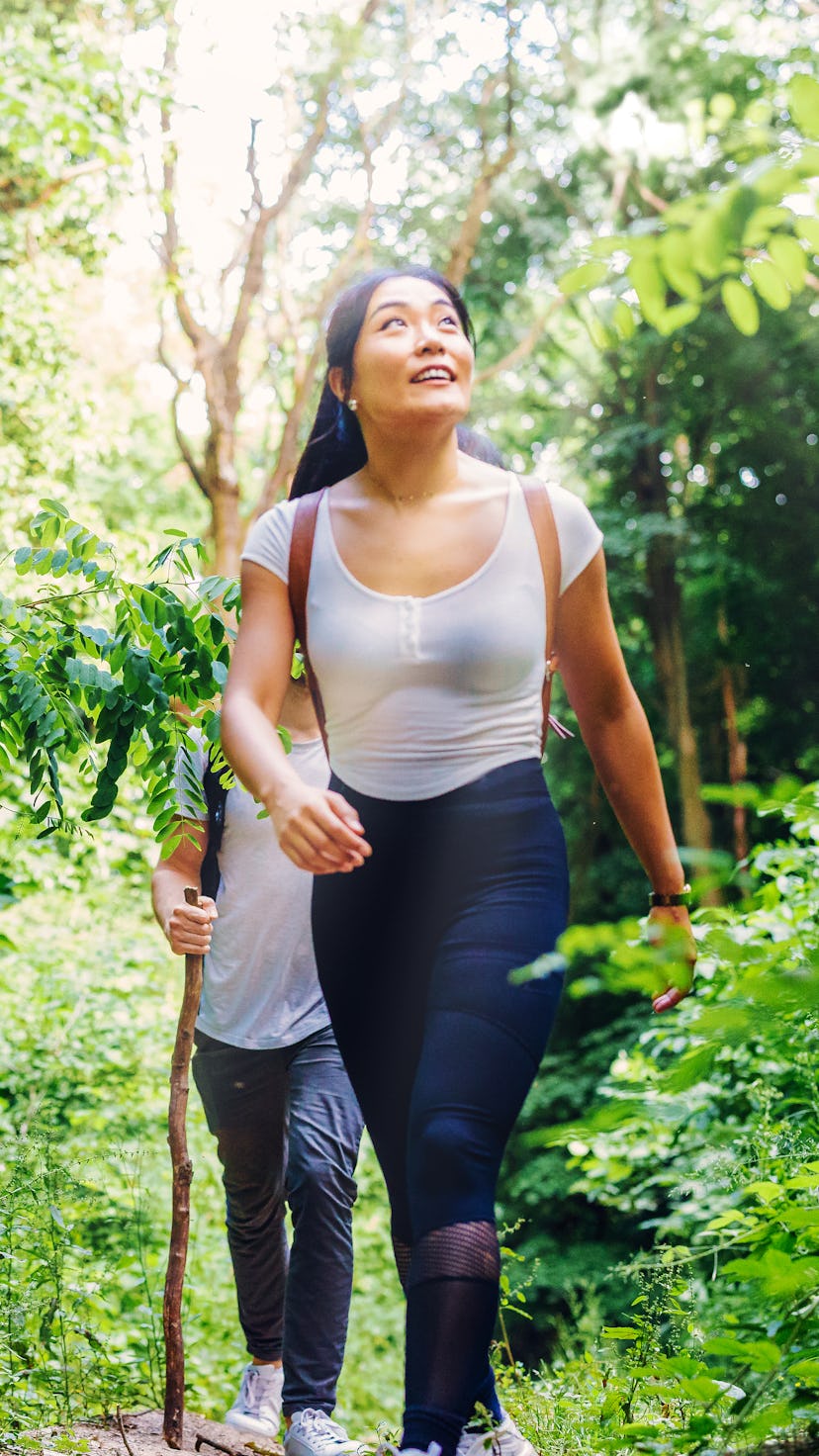 A person wears a white shirt while walking in front of a friend on a trail. You don't have to be sit...