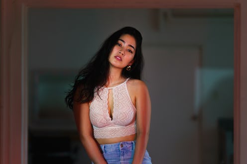 A portrait of a seductive woman lit by vibrant neon colored lights.