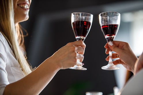 Close up shot of two unrecognizable women cheering to friendship and good health with glasses of red...