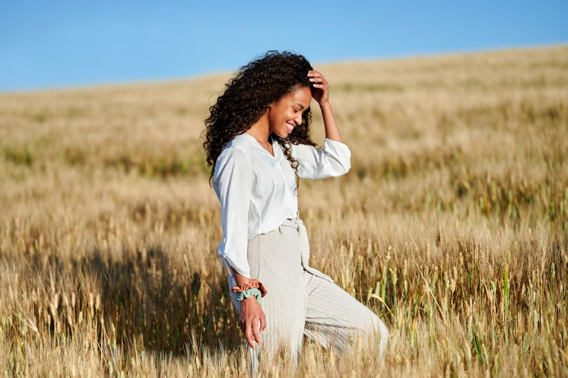 A person smiles as they walk through a field. Walking meditations are about slowing down your though...