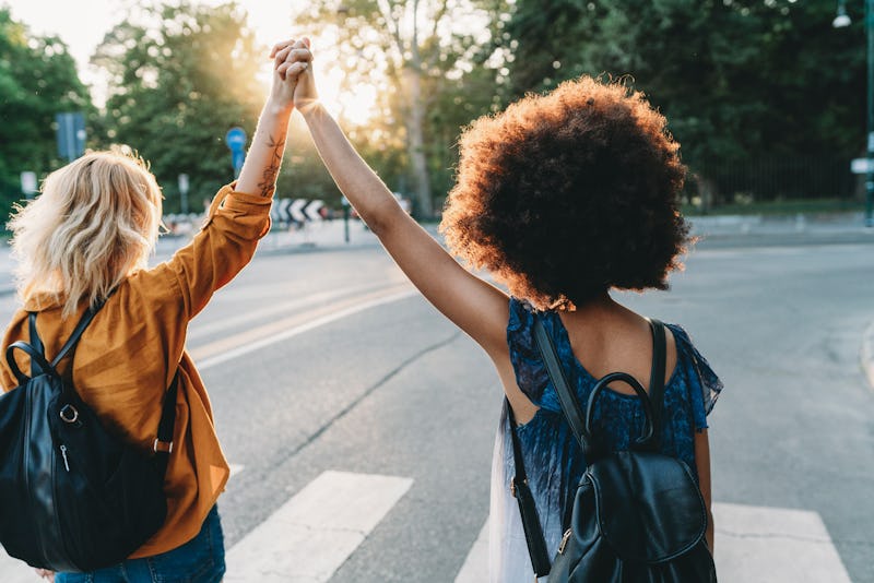 Two friends walking together in the city at sunset pivot away from a hug. Post-pandemic friendship a...