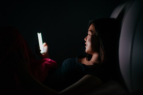 A woman uses her smartphone in the dark. Opal screen time blocker app makes you use your phone more ...