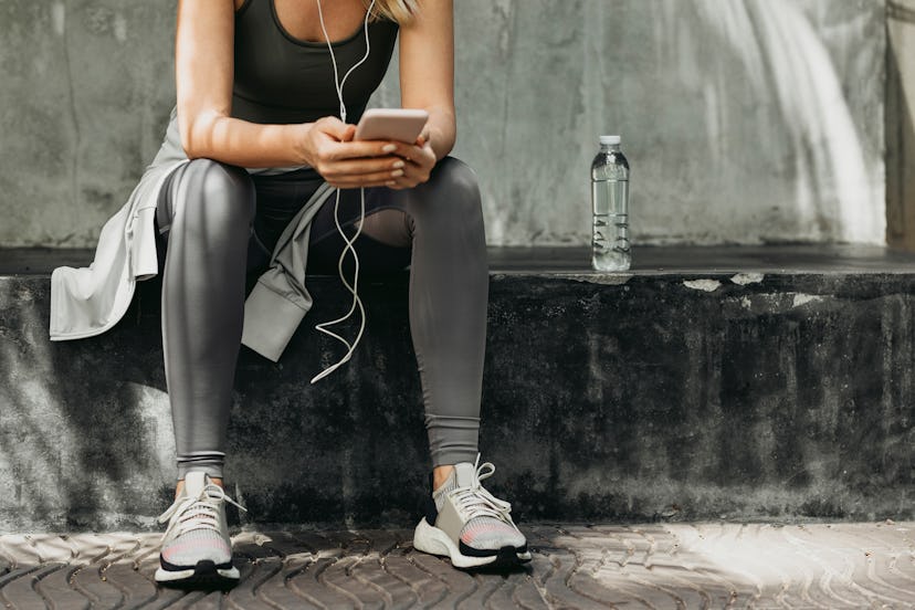 Woman takes a moment to check social media on her smartphone during a running session.