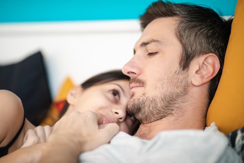 Young couple lying in bed in the morning close to each other, waking up and snuggling