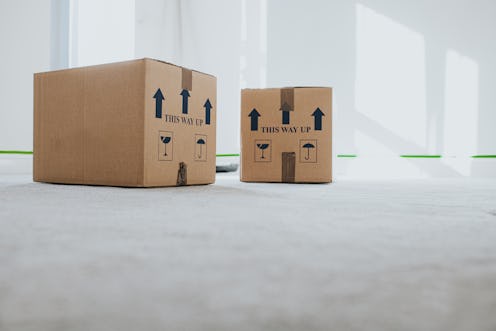 Conceptual image of cardboard boxes stacked in a neutral empty sunny room. Space for copy.