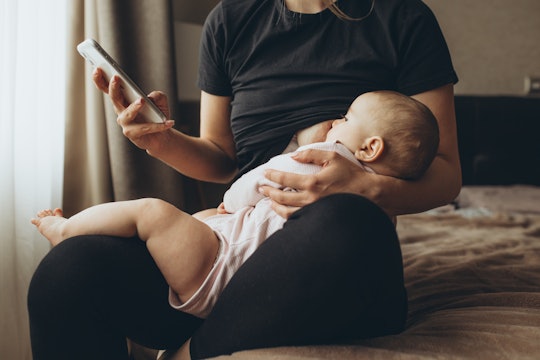 Mother breastfeeding her baby with phone