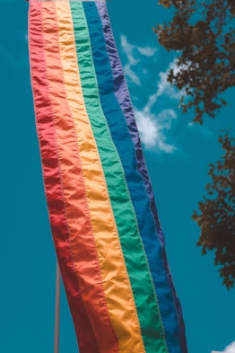 A long pride flag flies against a blue sky. Here's why rainbows are associated with LGBTQ+ Pride. 