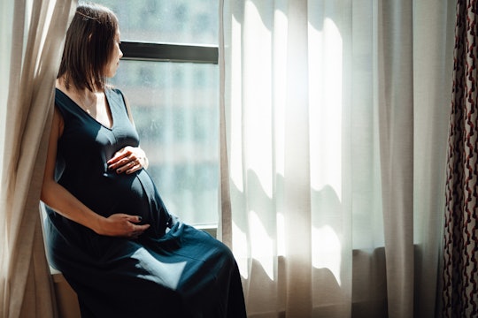 pregnant woman sitting by window looking outside