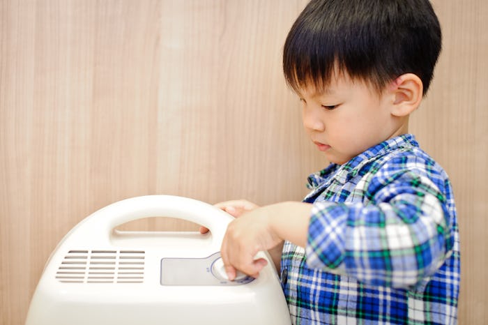 The little boy hand turn off the dehumidifier in the bedroom.