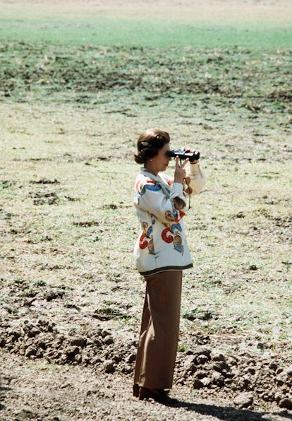 Queen Elizabeth II watches the wildlife through a pair of binoculars while on Safari in Zambia in 19...