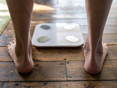 UK, East Sussex, Close-up of senior mans feet at bathroom scale