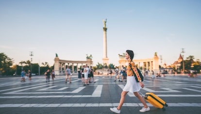 Young woman with suitcase just arriving in Budapest and walking through Hero’s square