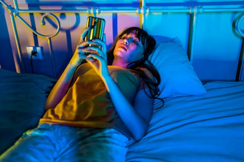 A young woman watches TikTok before bed. Here's how watching TikTok affects your dreams.