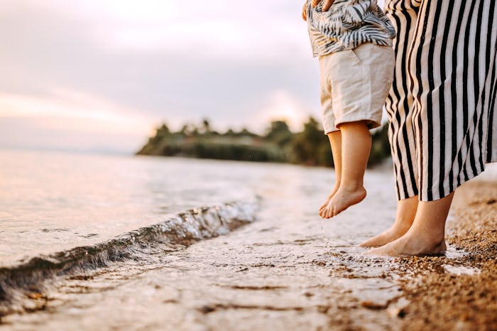 Mother and baby feet at the sea at the sunlight water is moving