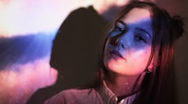 Young woman illuminated in purple light and sparkles to show the spiritual meaning of the July 2021 ...