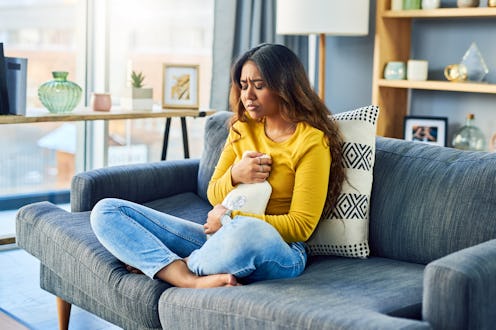 Shot of a young woman suffering from stomach cramps at home
