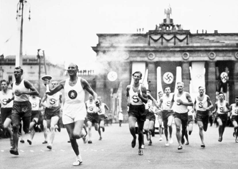 1 Aug 1936:  The torch bearer runs through the streets en route to the Olympic Stadium in Berlin, Ge...