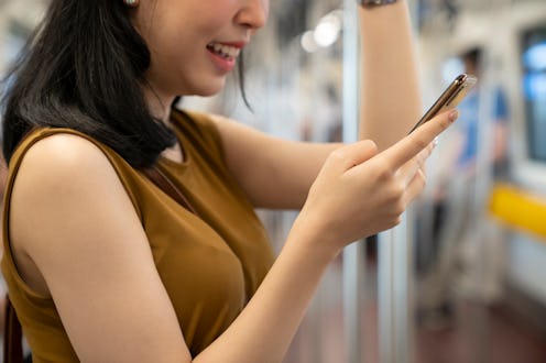 woman reading her phone on the subway