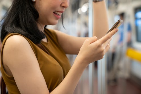 woman reading her phone on the subway