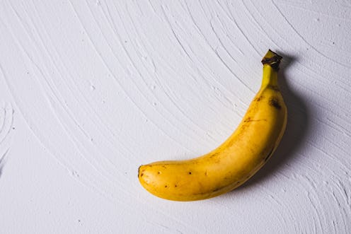 overhead view of a single banana against white plaster background
