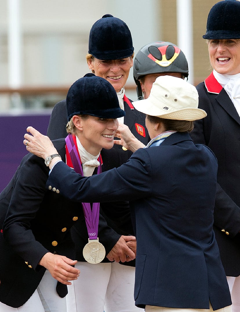 Britain's Zara Phillips (L) receives a silver medal from her mother Princess Anne after she and team...