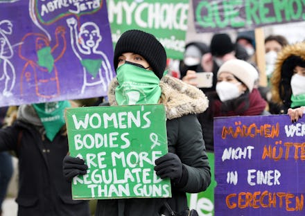20 March 2021, Bavaria, Munich: A woman carries a sign reading "Women's Bodies are more regulated th...