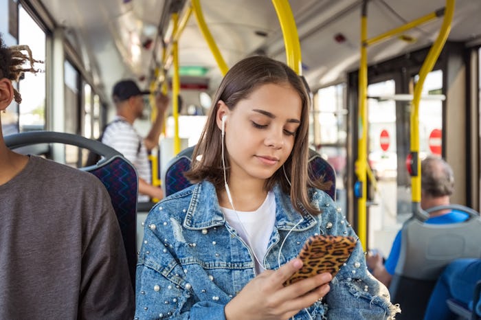 teen girl listening to podcast on bus.