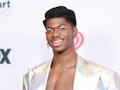 Lil Nas X on a red carpet wearing a silver metallic winged eyeliner to match his silver holographic ...