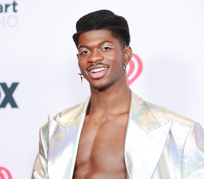 Lil Nas X on a red carpet wearing a silver metallic winged eyeliner to match his silver holographic ...