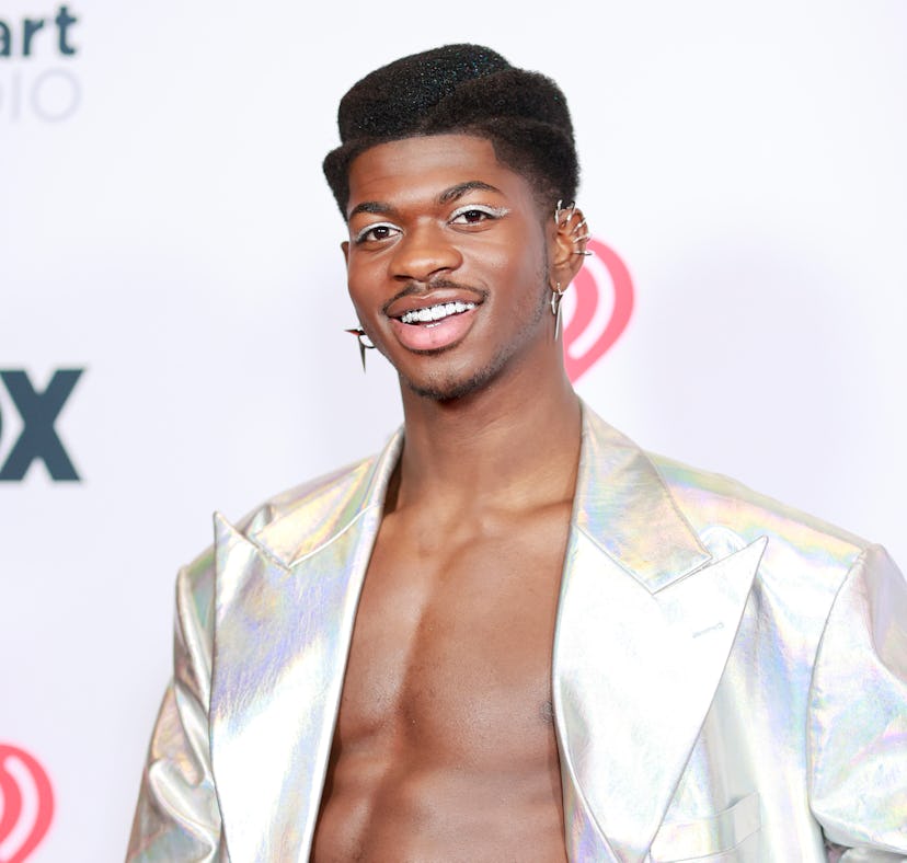 Lil Nas X on a red carpet wearing a silver metallic winged eyeliner to match his silver holographic ...