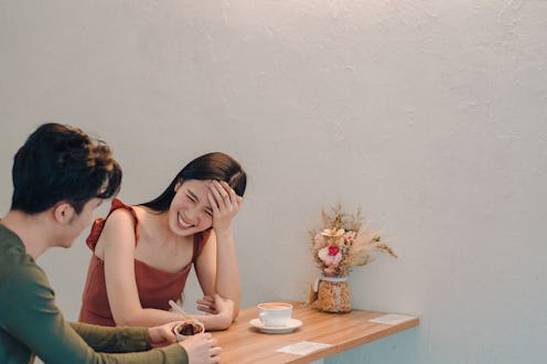 Young Asian man and woman having a lively conversation in a cafe