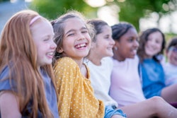 A group of elementary age children around ten years old are hanging out together outdoors. The focus...