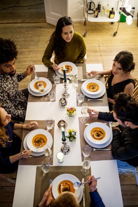 High angle view of multi-ethnic friends having squash soup at dinning table